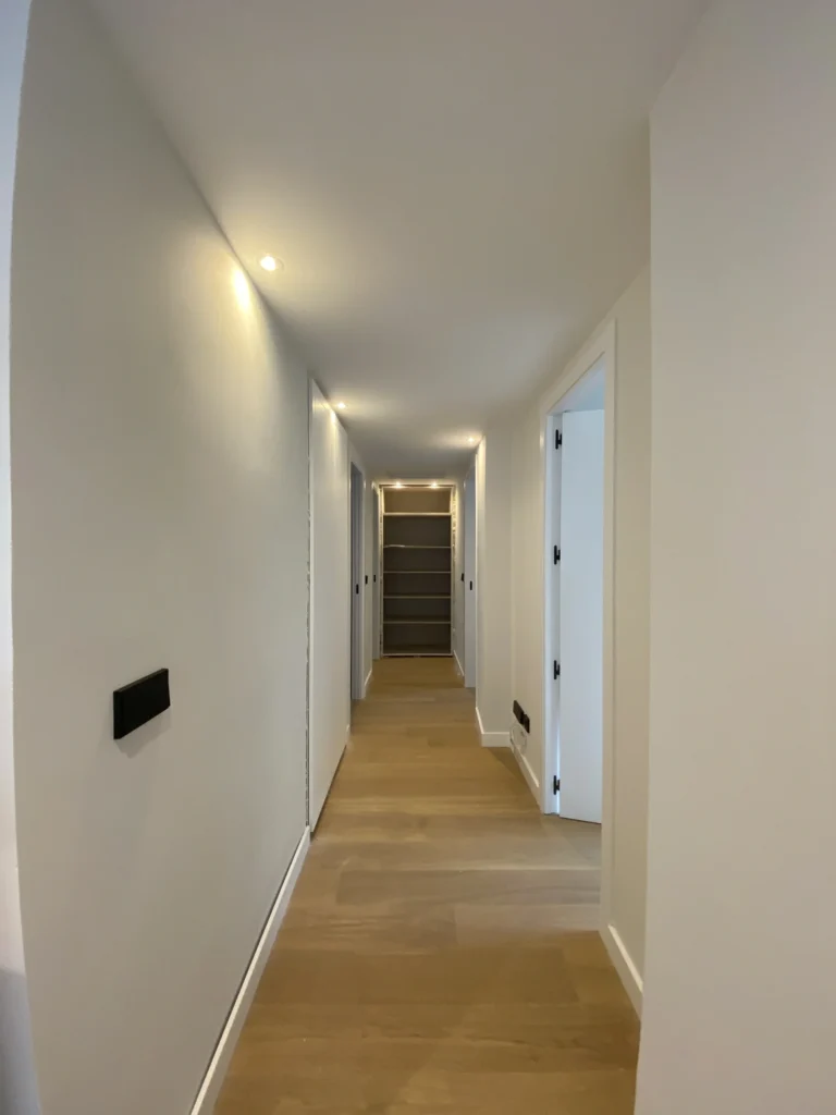 Pasillo de la vivienda reformada en color gris con rodapies blancos