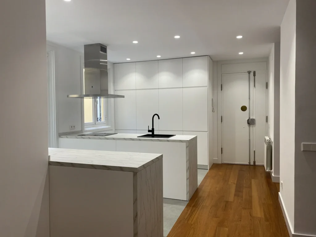 Cocina minimalista blanca con encimera mármol en el centro de Madrid, reformas integrales modernas cerca de Gran Vía