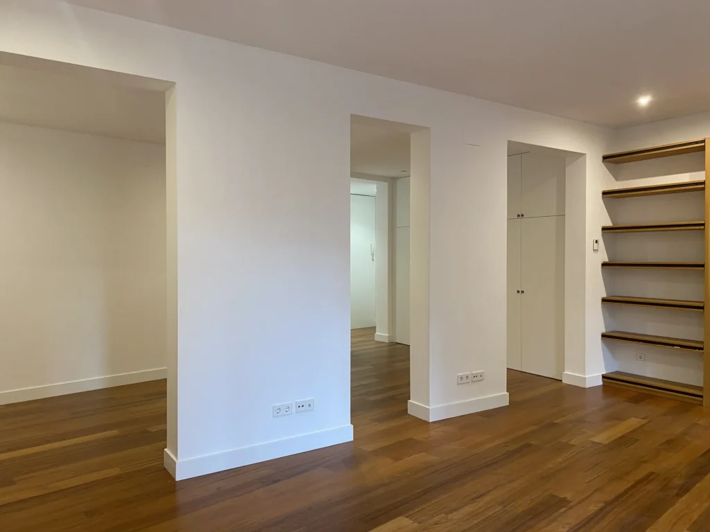 Pasillo con arcos y suelo madera en zona de Cortes-Justicia, diseño interior fluido y minimalista
