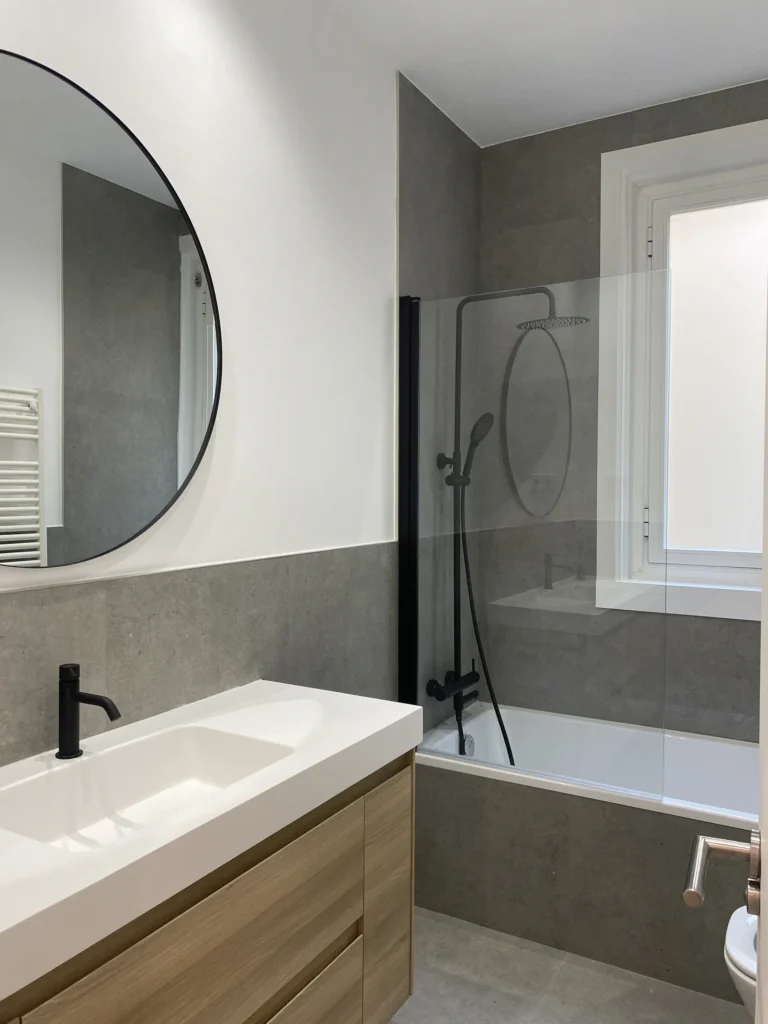 Baño reformado con ducha walk-in, espejo redondo y azulejos grises en Reforma en Justicia cerca de Sol, Mokara Estudio